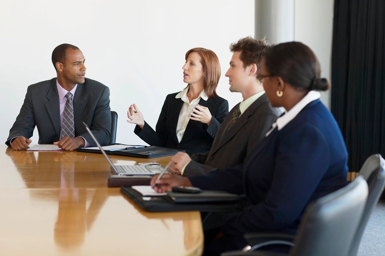A group of people sitting at a table with laptops.