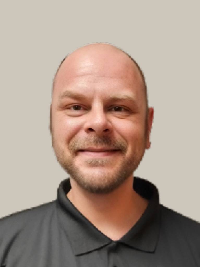 Smiling bald person in black polo shirt